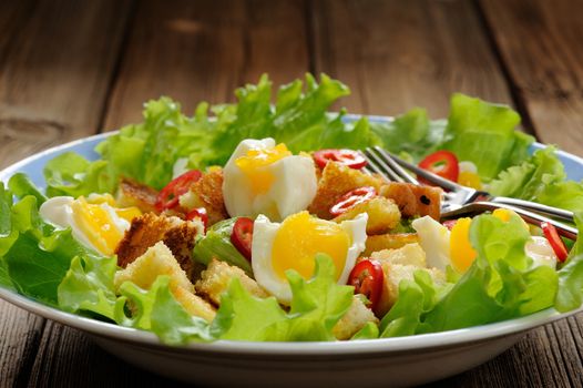 Salad Caesar with eggs, chili pepper and two forks closeup horizontal