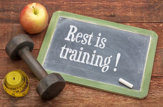 rest is training - recivery concewpt -  slate blackboard sign against weathered red painted barn wood with a dumbbell, apple and tape measure