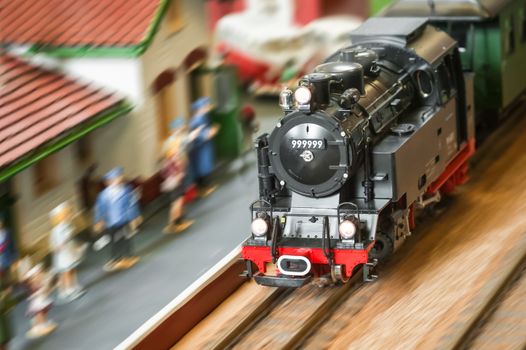 model railroad steam locomotive (with fake number) speeding through a station