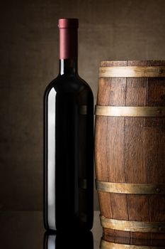 Red wine in a bottle near wooden barrel