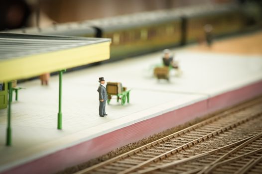 miniature model of a well dressed man waiting for a train - shallow d.o.f