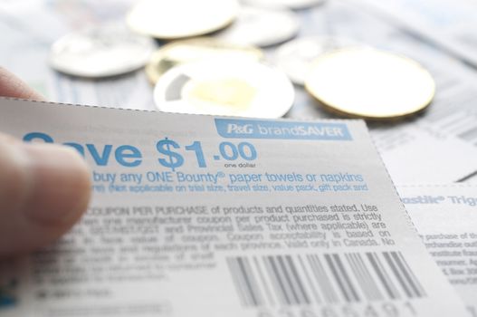 Coquitlam BC Canada - July 22, 2014 : Holding Canadian saving coupons with money. All coupons for Canadian store, they are issued by manufacturers of consumer packaged goods Canada.  