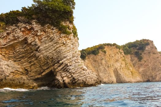 The rocks over the transparent ocean water. Montenegro. Rafailovici