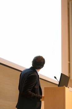 Speaker giving talk on podium at Business Conference. Business and Entrepreneurship. Expert presenting his work in lectures hall. Copy space.