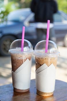 Coffee ice. Plastic glass is placed on a wooden table.