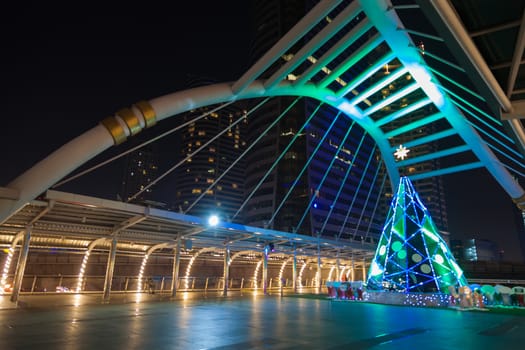 Christmas tree on the bridge walkway. Light decorations during Christmas. The office building in Bangkok.