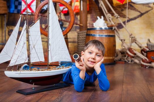 Cute little boy with ship toy on the deck of a ship