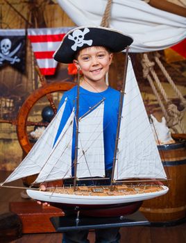 Cute little boy with ship toy on the deck of a ship