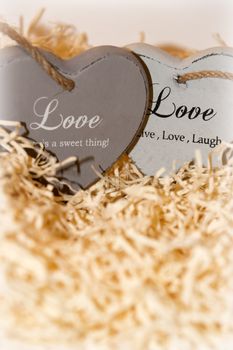 two grey wooden love hearts in a love nest made of straw with loving inscriptions