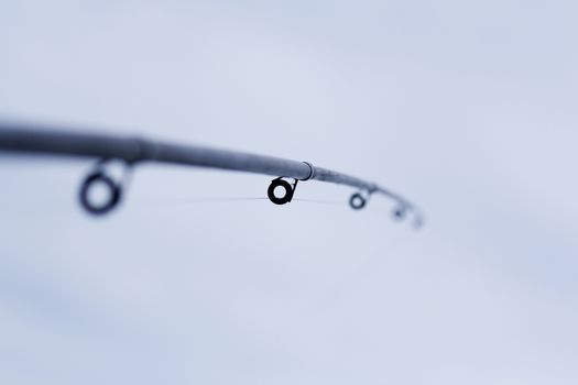 Closeup fishing rod and fishing line is threaded through the rings.