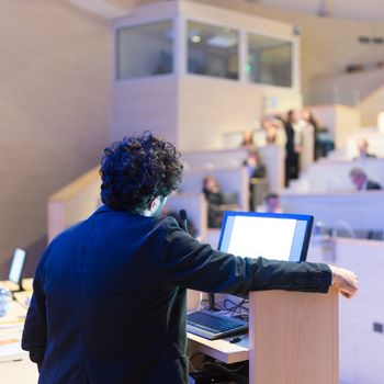 Speaker giving talk on podium at Business Conference. Business and Entrepreneurship. Expert presenting his work in lectures hall.