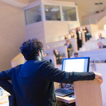 Speaker giving talk on podium at Business Conference. Business and Entrepreneurship. Expert presenting his work in lectures hall.