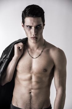 Portrait of a Young Vampire Man with Black Leather Jacket, Showing his Torso,  Chest and Abs, Looking at the Camera, on a White Background.