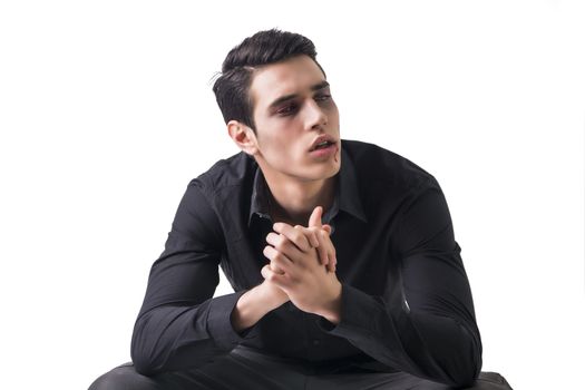 Portrait of a Young Vampire Man with Black Shirt Sitting on Floor with Hands Joined, Isolated on White