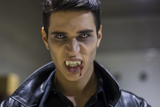 Close up Face of a Handsome Vampire Man in Leather Clothing, with Blood on his Mouth, Looking at the Camera.