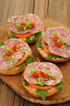 Ham sandwiches with chili, parsley and scallion on wooden board vertical
