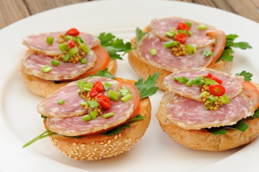 Ham sandwiches with chili, parsley and scallion on white plate closeup horizontal