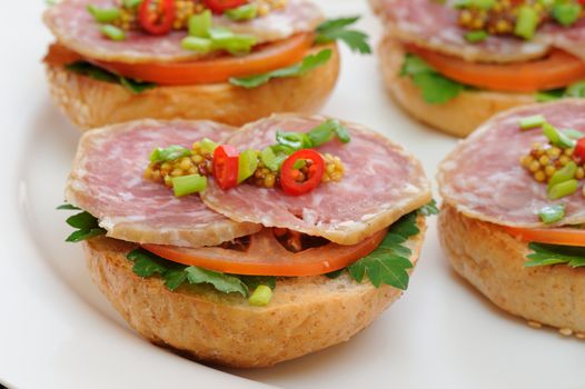 Ham sandwiches with chili, parsley and scallion on white plate closeup horizontal