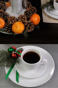 Cup of coffee with fir branches on a saucer on the Christmas table