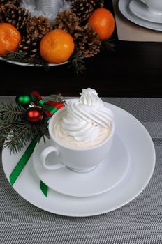 Cup of coffee with fir branches on a saucer on the Christmas table