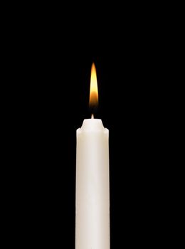 A burning white candle on a black background.