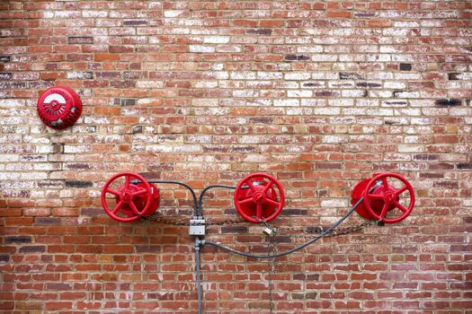 Red Sprinkler Valves against Red Brick Background; Exterior Building