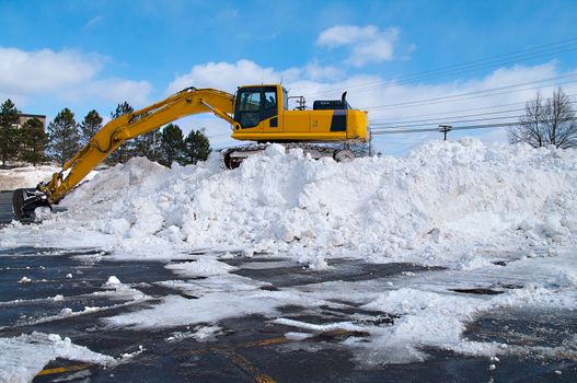 Excavator clearing snow in a parking lot 