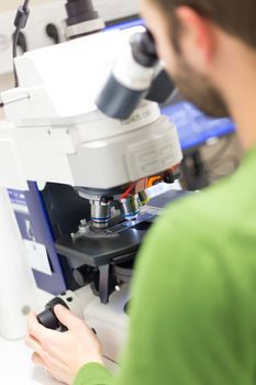 Male scientist microscoping on hi-tec fluorescent microscope. 