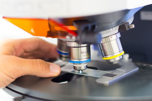 Scientist microscoping on hi-tec fluorescent microscope. . Health care professional in hes working environment.