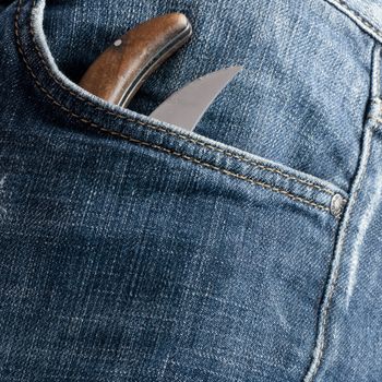 knife in the pocket in front of an old jeans