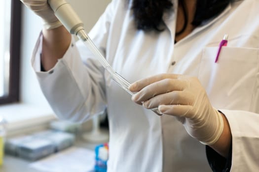 Closeup of a female scientist filling test tube with pipette in lab