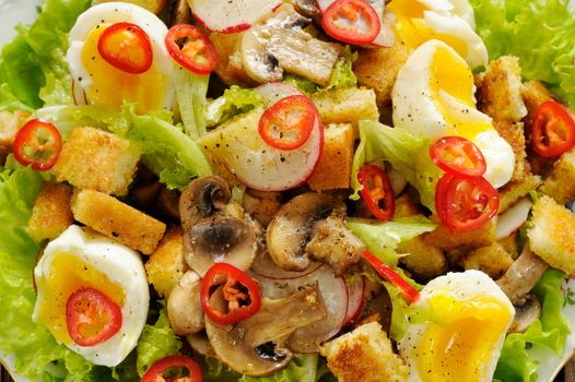 Salad Caesar with mushrooms, eggs, chili and radish with two forks on wooden background closeup horizontal