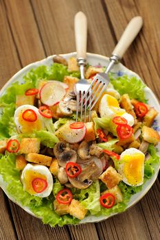 Salad Caesar with mushrooms, eggs, chili and radish with two forks on wooden background vertical