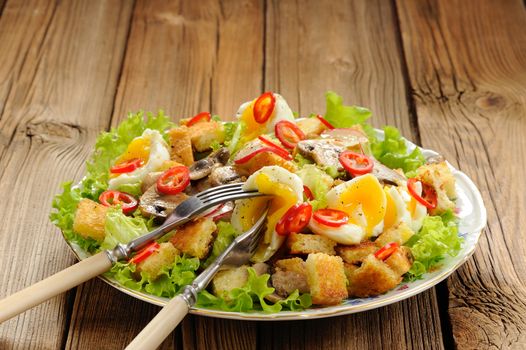 Salad Caesar with mushrooms, eggs, chili and radish with two forks on wooden background horizontal