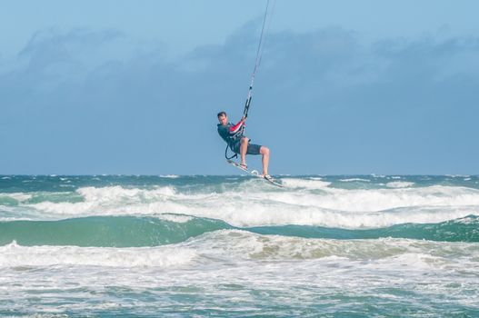 MOSSELBAY, SOUTH AFRICA - DECEMBER 31, 2014: A stormwind lifts an unidentified windsurfer high above the waves at the Klein Brakrivier beach