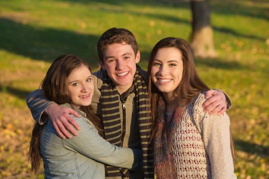 Smiling handsome teen male with happy girlfriends outdoors