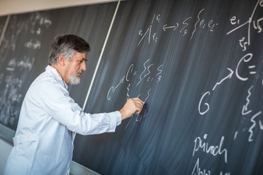 Senior chemistry professor writing on the board while having a chalk and blackboard lecture (shallow DOF; color toned image)