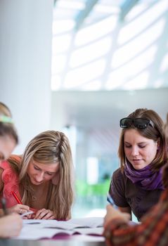 Group of college/university students during a brake between classes - chatting, comparing notes, having fun (shallow DOF; color toned image)