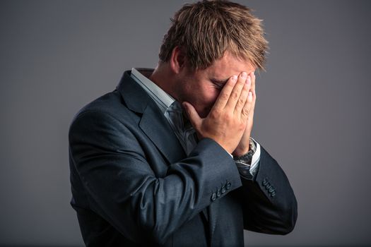 Businessman in depression with hands on forehead, hoping for better days to come as he has just hit the bottom