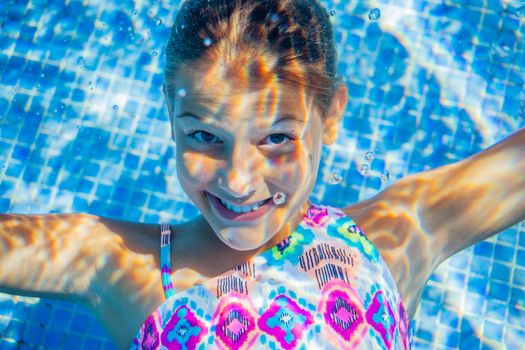 Close-up portrait of underwater happy cute girl in swimming pool