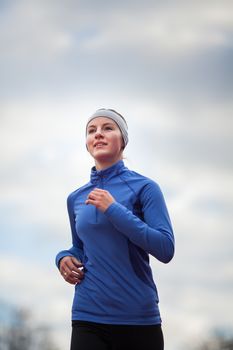 Portrait of a woman running against against blue sky