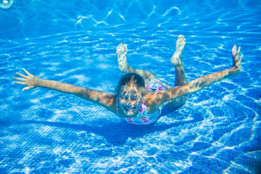 Underwater happy cute girl in swimming pool