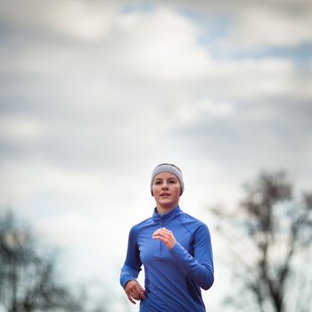 Portrait of a woman running against against blue sky