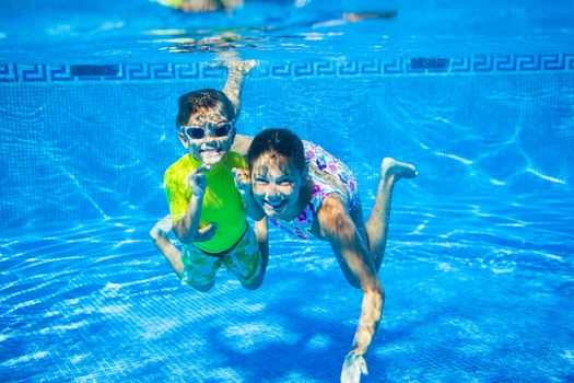 Underwater happy cute girl and boy in swimming pool