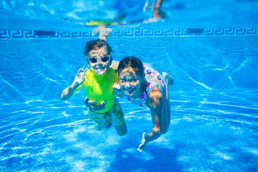 Underwater happy cute girl and boy in swimming pool