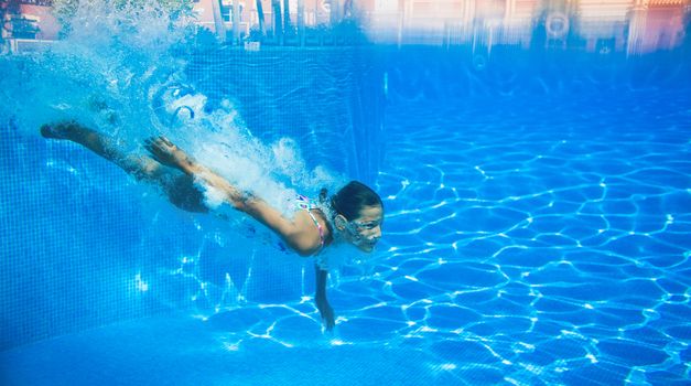 Underwater happy cute girl in swimming pool