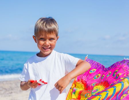 Summer vacation - Portrait of cute boy flying kite beach outdoor.