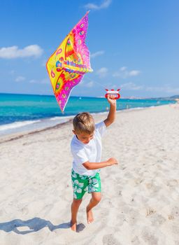 Summer vacation - Cute boy flying kite beach outdoor.