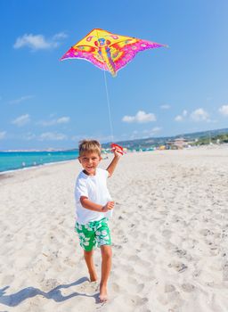 Summer vacation - Cute boy flying kite beach outdoor.