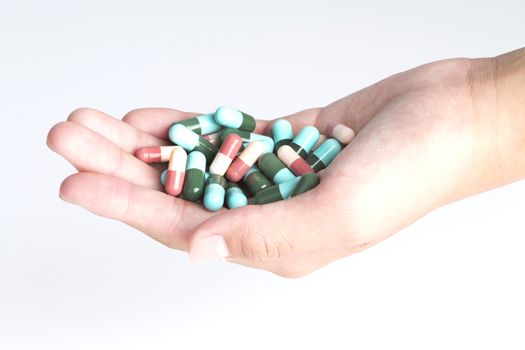 Stack of different pills in the hands over white background
